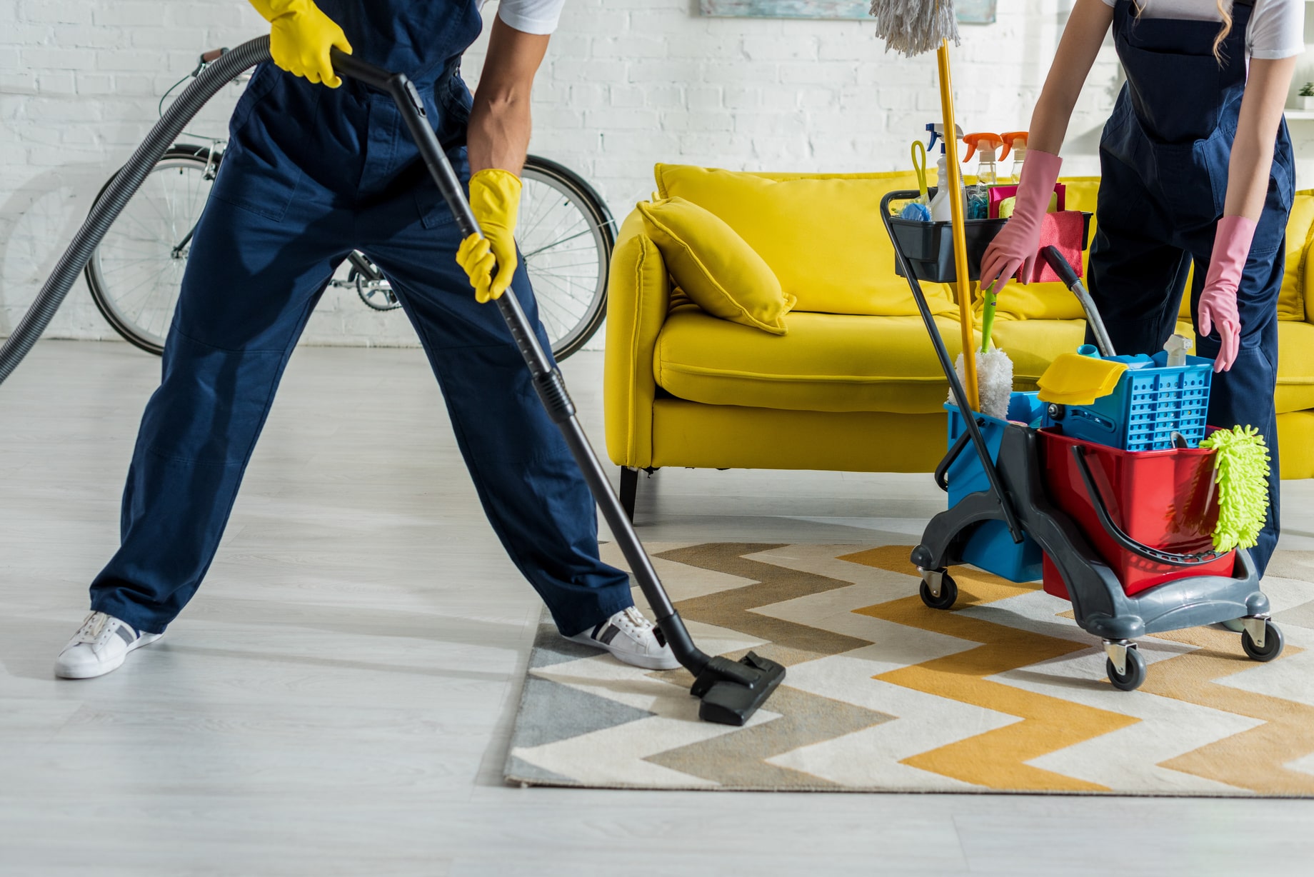 Zwei Reinigungskräfte saugen und reinigen eine helle Wohnung